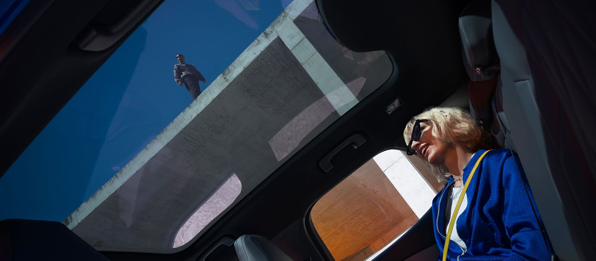 Iemand zit in de nieuwe Ford Capri® en geniet van het panoramische glazen dak.