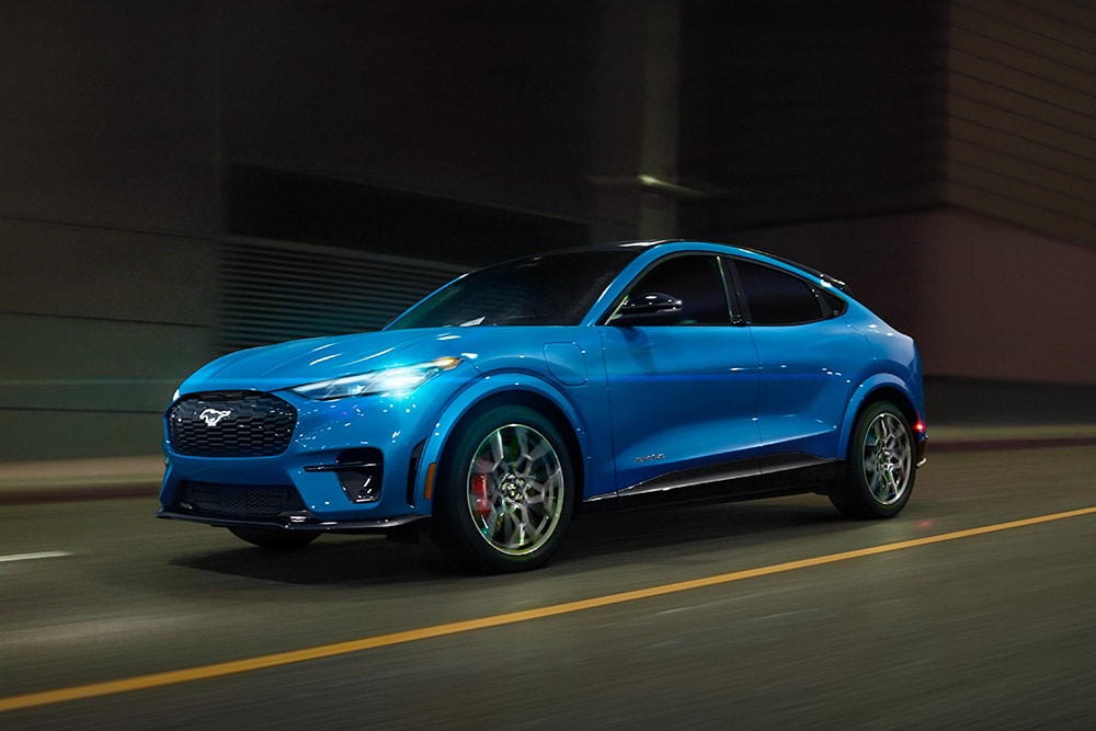 Een blauwe, elektrische Ford Mustang Mach-E GT-sportwagen die over een lege weg rijdt.