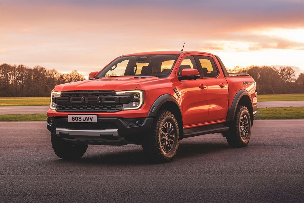 Een oranje Ford Ranger Raptor-pick-uptruck geparkeerd in een mooi landschap.