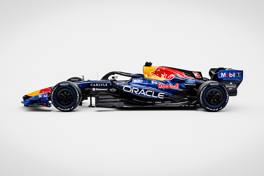 Een gestroomlijnde Red Bull Ford Formule 1-raceauto tegen een strakke witte achtergrond met sponsorlogo’s van Ford en Red Bull.