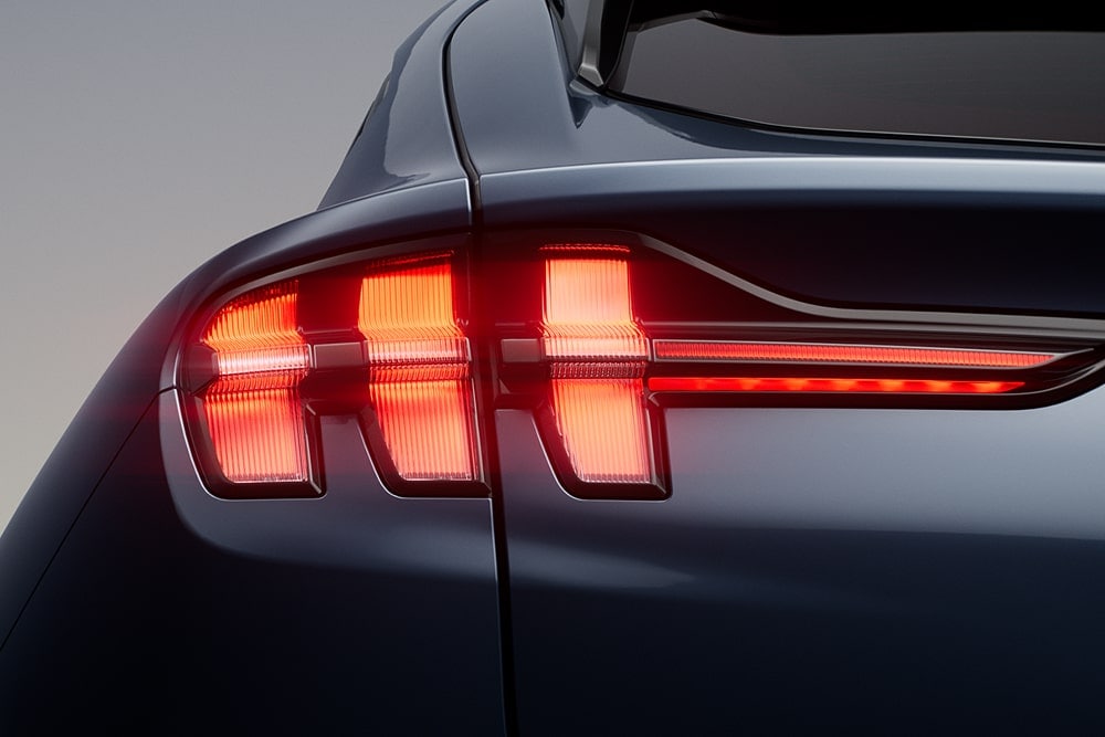Close-up van verlichte driedubbele achterlichten op een Ford Mustang Mach-E sportauto.