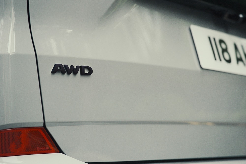 De achterkant van een zilveren Ford Tourneo Custom, met het AWD-badge.