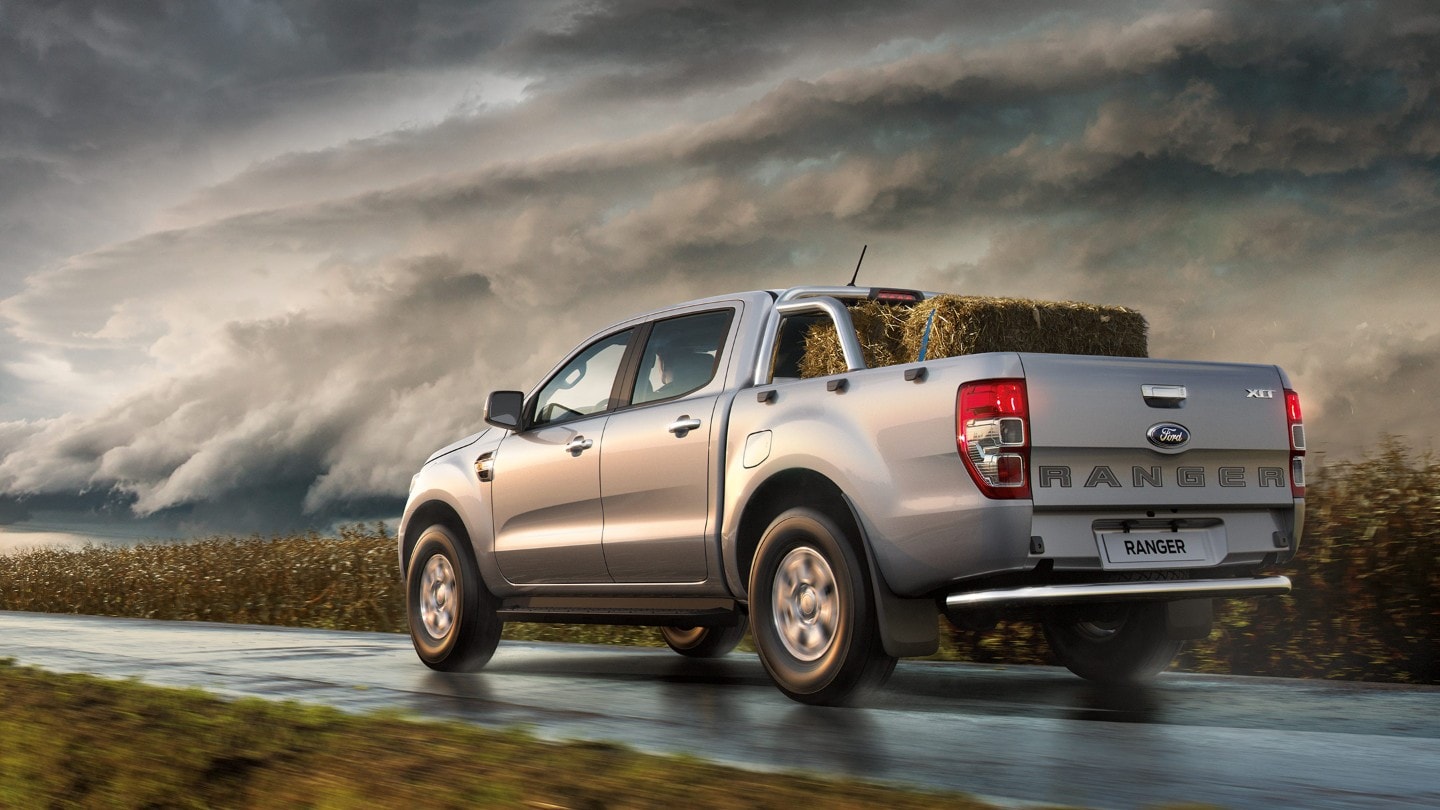 Silver Ford Ranger rear view driving on wet road