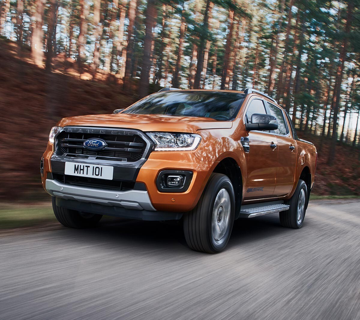 Oranje Ford Ranger Wildtrak rijdt door bos, vooraanzicht
