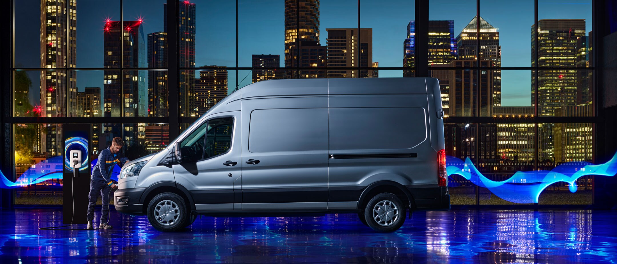 New E-Transit side view with the backdrop of city in night with blue electric lights