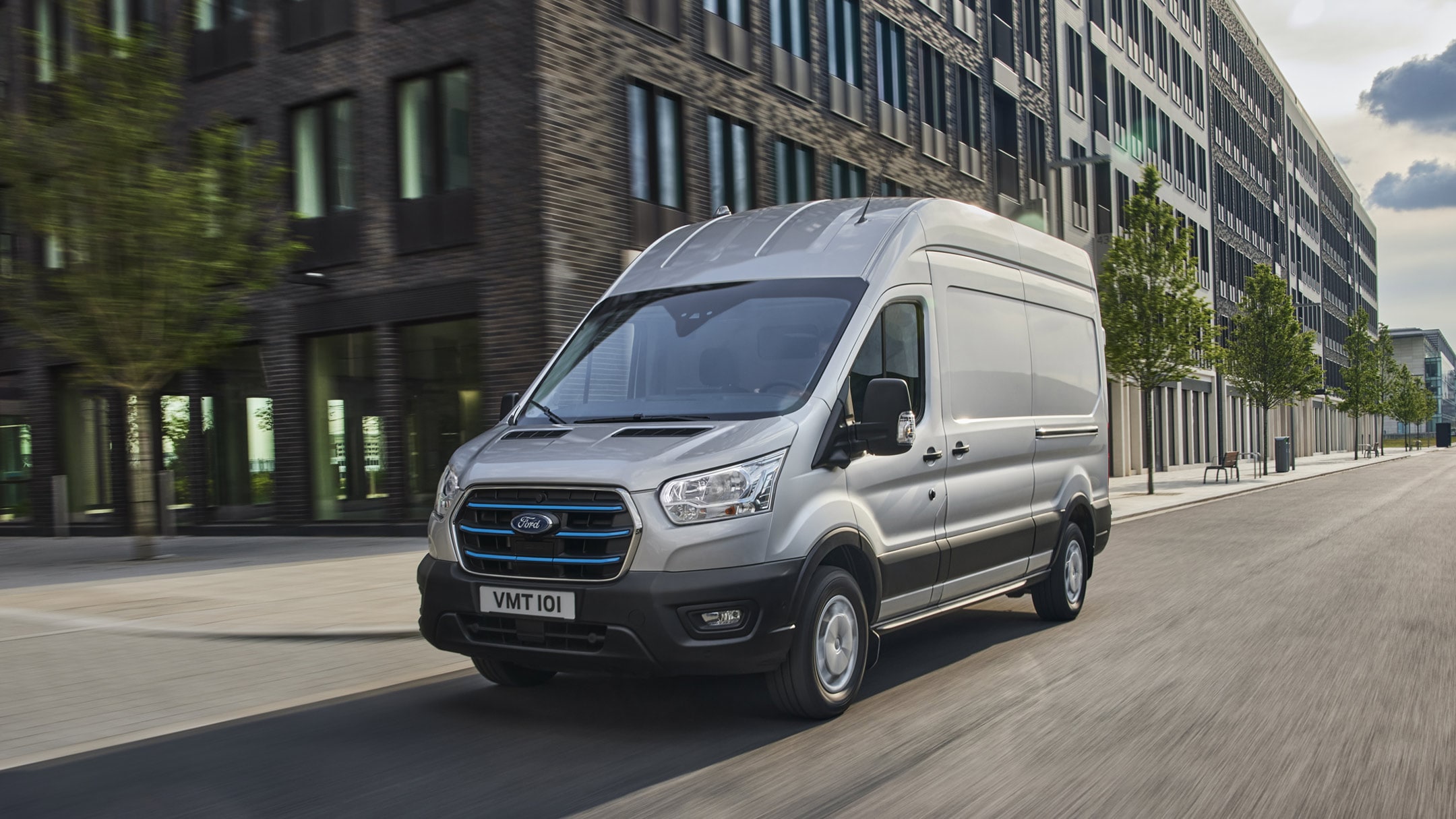 New Ford E-Transit driving through city 3/4 front view