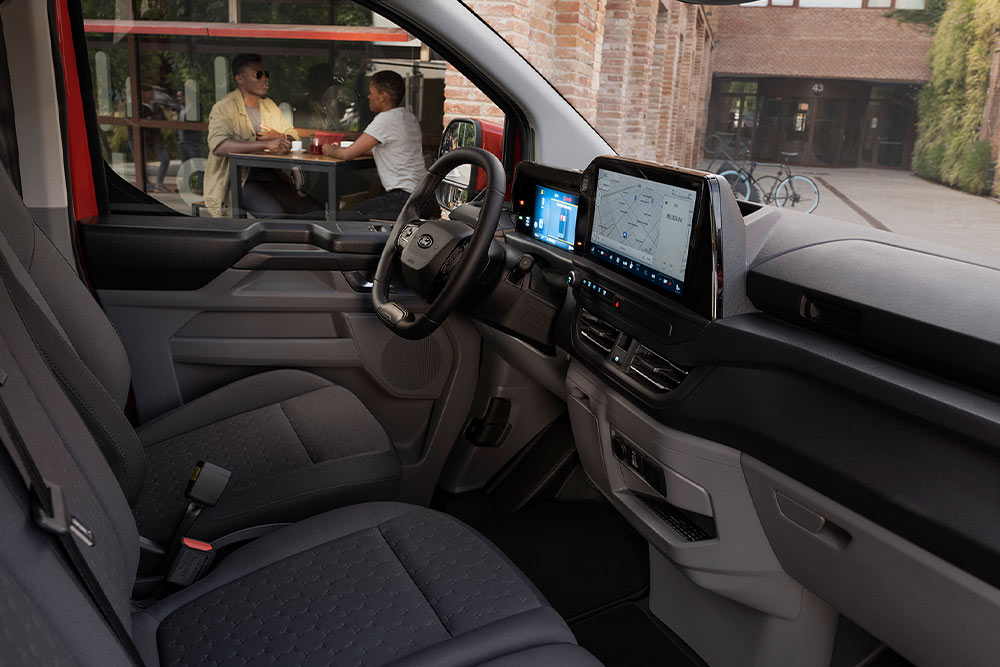 Iemand aan het stuur van een rode Ford E-Transit Custom elektrische bestelwagen.