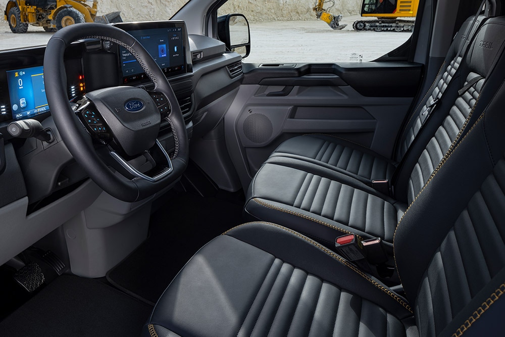 Interieur van een Ford E-Transit Custom Sport elektrische bestelbus met zwart met goudkleurige stoelen.