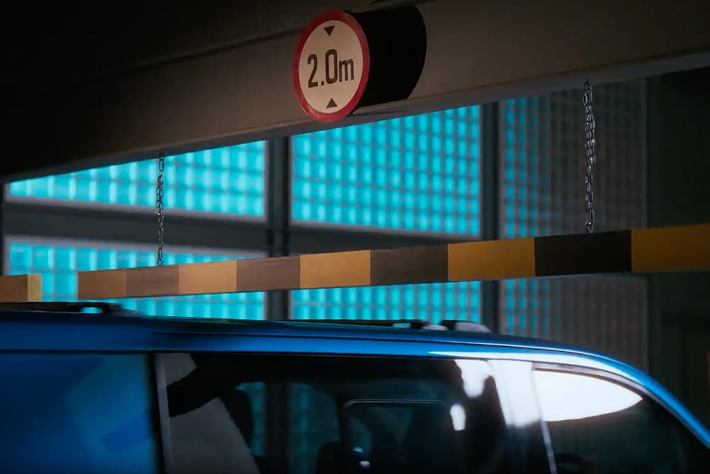 Een blauwe Ford E-Transit Custom elektrische bestelbus rijdt een parkeergarage binnen.