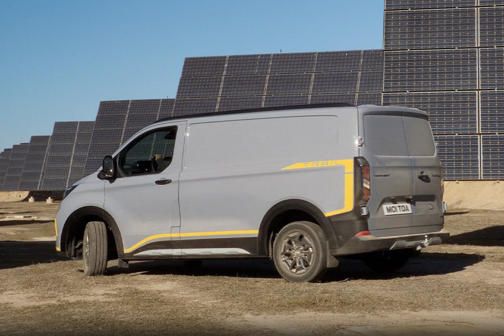 Grijze Ford Transit Custom Trail-bestelwagen met gele accenten.