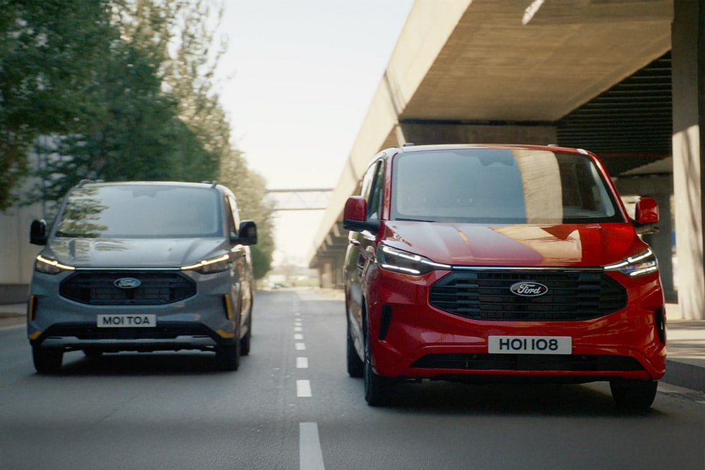 Een grijs met rode Ford Transit Custom-bestelwagen rijdt op de snelweg.