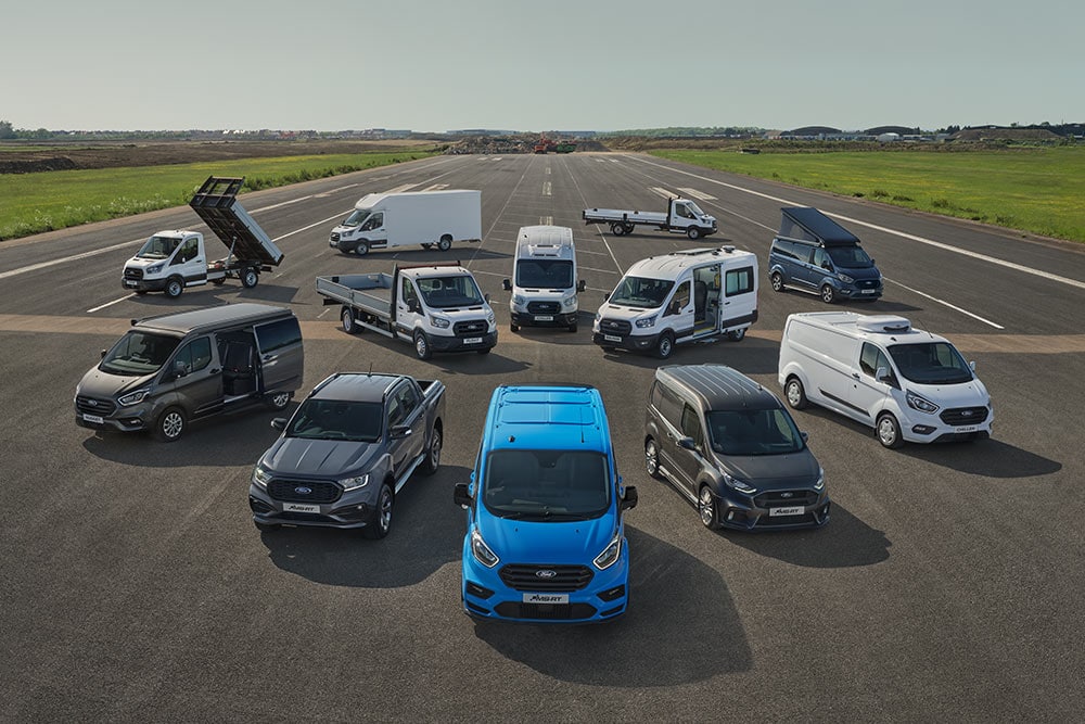 Een verzameling geparkeerde Ford-bestelwagens en pick-ups, die de diversiteit van de beschikbare modellen laat zien.