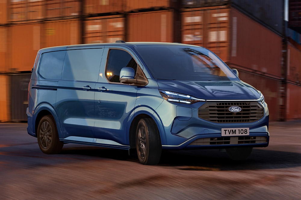 Een blauwe Ford Transit Custom Plug-In Hybrid bestelwagen rijdt over een haventerrein.