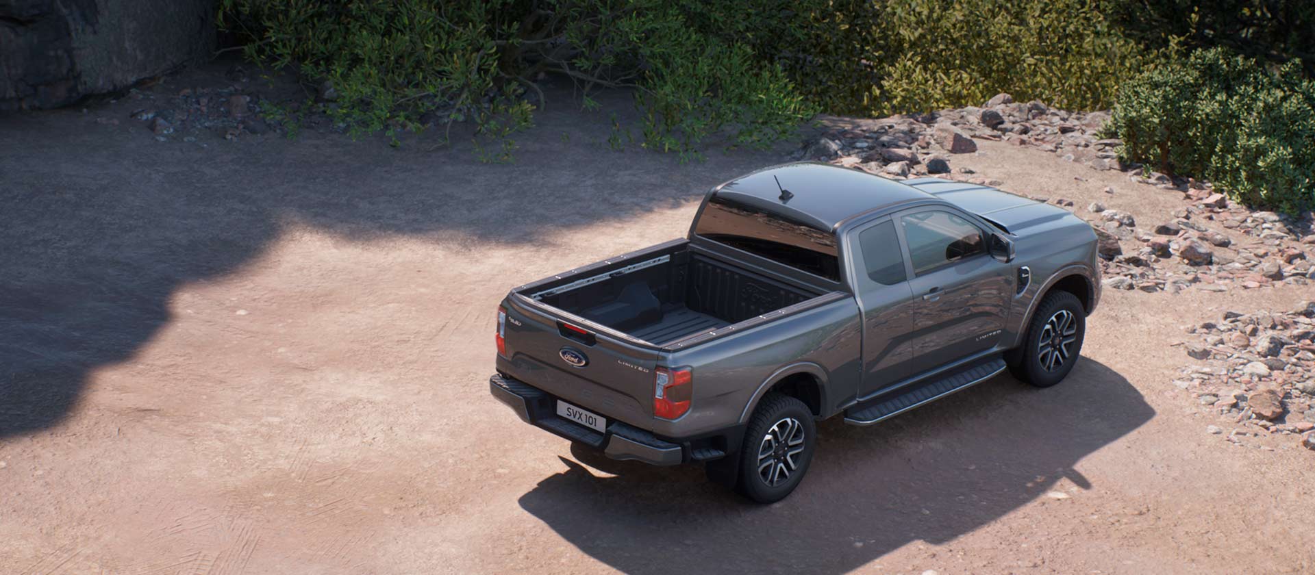 Een grijze Ford Ranger met supercabine, geparkeerd op een onverharde weg.