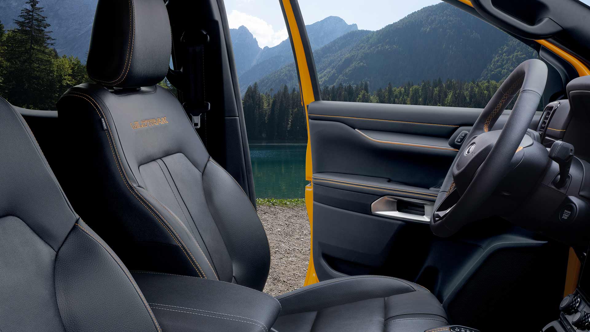 Binnenaanzicht van een Ford Ranger Wildtrak met zwart lederen stoelen en geel geborduurd 'Wildtrak'-logo.
