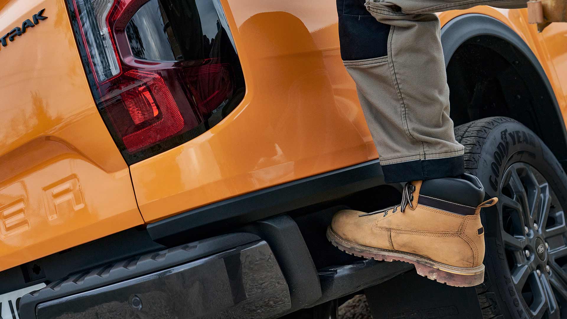 Een bouwvakker die op de geïntegreerde achterste trede van de Ford Ranger stapt.