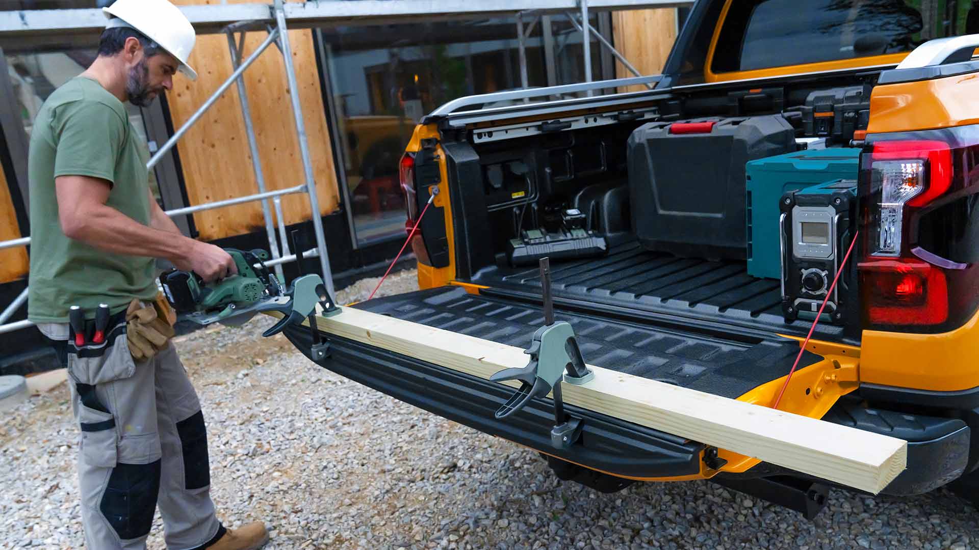 Een bouwvakker die de achterklep van de Ford Ranger Wildtrak als werkbank gebruikt.