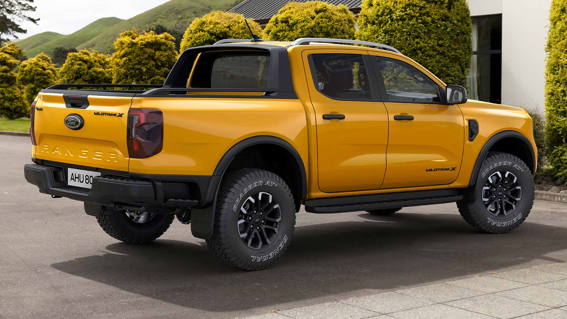 Een gele Ford Ranger met dubbele cabine, geparkeerd op een verharde oprit.