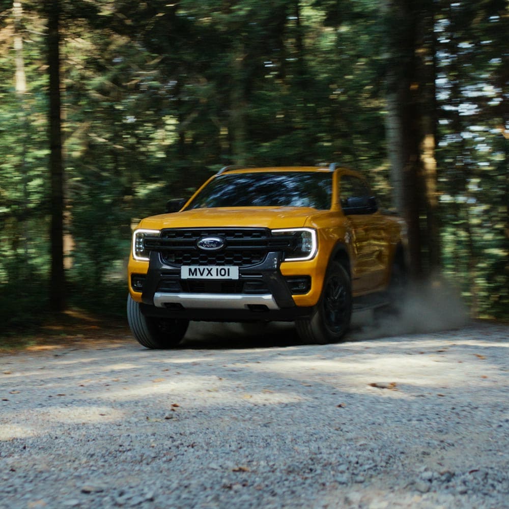 Video van een gele Ford Ranger Wildtrak met dubbele cabine die over bergwegen en grindpaden rijdt.