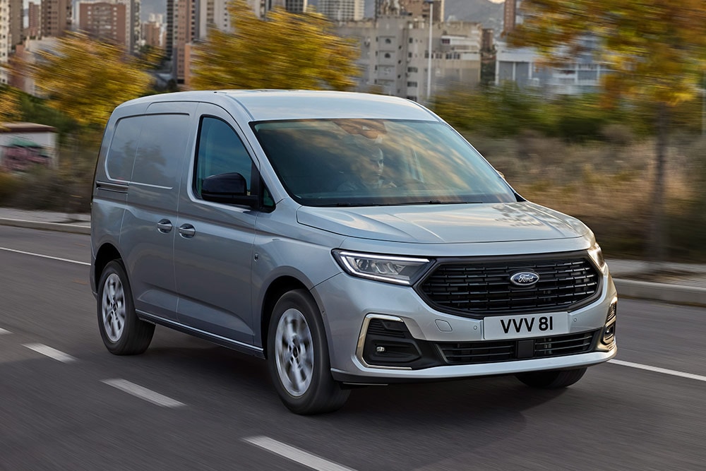 Een Ford Transit Connect rijdend in een stad, met verchroomde mistlichtomlijstingen en automatische koplampen.