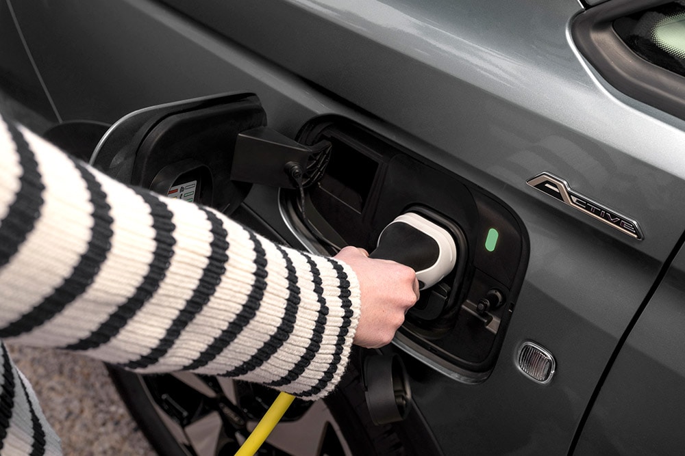 Een persoon sluit een oplaadkabel aan op een Ford Transit Connect plug-in hybride.
