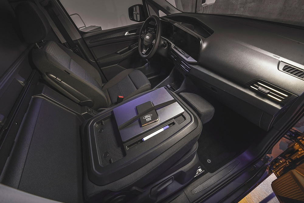 Interieur van de Ford Transit Connect met dashboard, stoelen, een laptop en telefoon op de middenconsole.