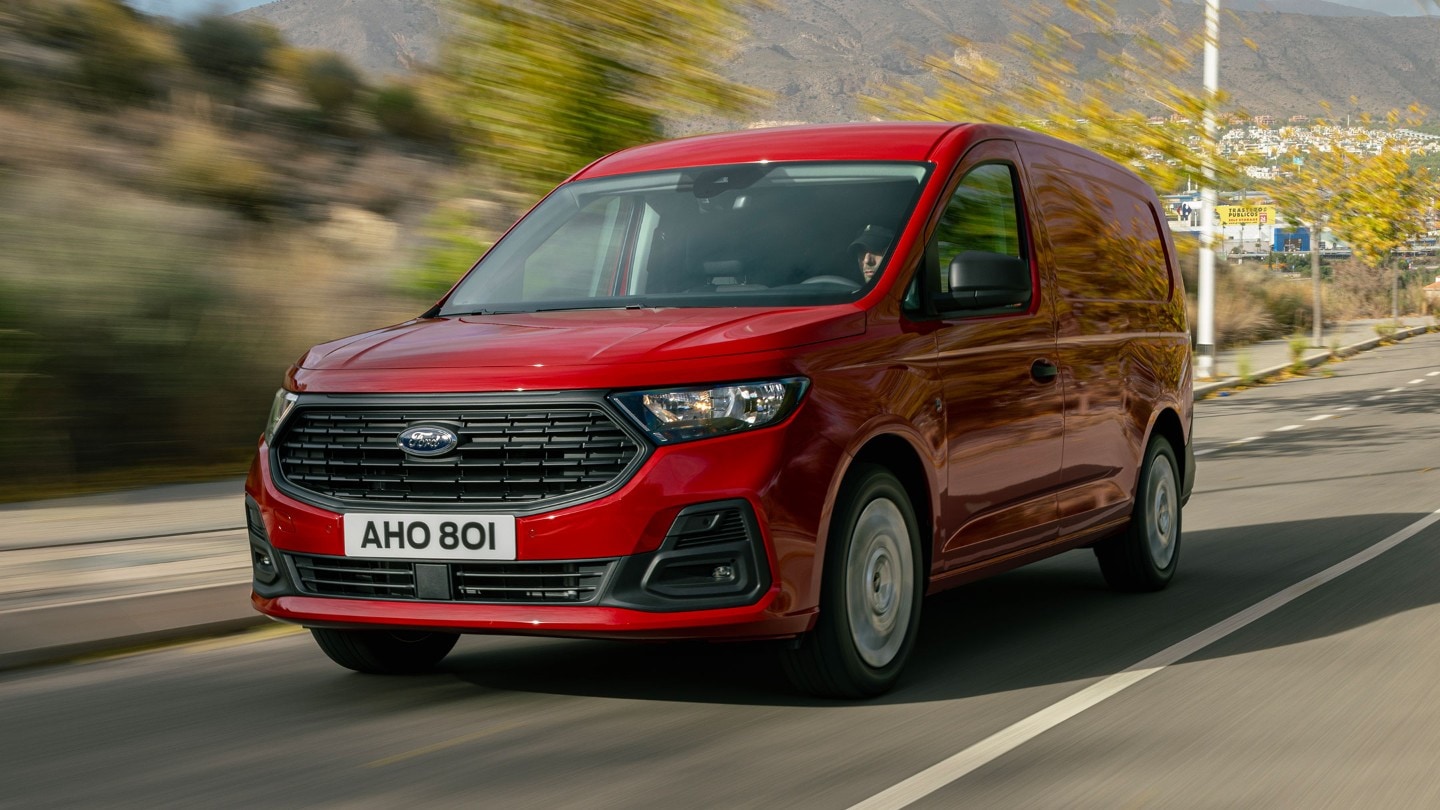 De nieuwe Ford Transit Connect in Maple Red met grille en koplampen rijdt langs een weg. 