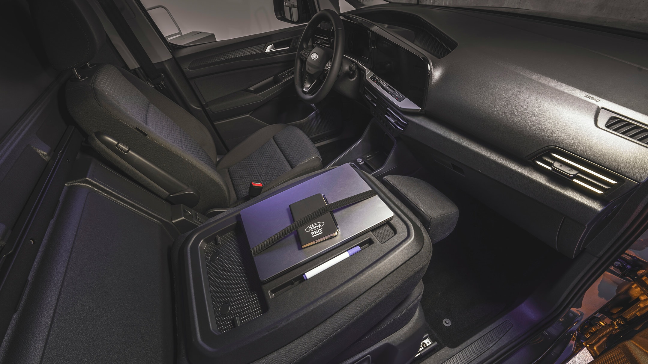 Een laptop en Ford Pro-notebook liggen op de werktafel van de nieuwe Ford Transit Connect.