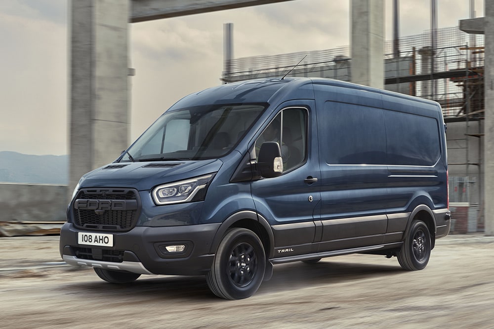 Een Ford Transit-bestelwagen met het optionele Trail-pakket die op een industrieterrein rijdt. 