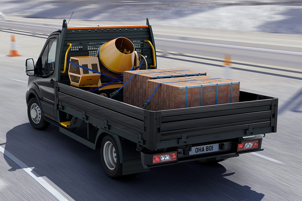 Een rijdende Ford Transit Chassis Cabine met lading achterin.