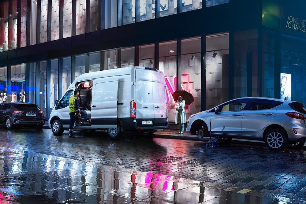 Een Ford Transit-bestelwagen van een bergingsbedrijf staat 's nachts geparkeerd in de stad.