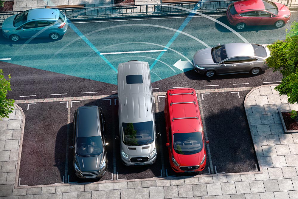 Een zilverkleurige Ford Transit-bestelwagen die achteruit rijdt, met blauwe lijnen die laten zien hoe de achteruitrijsensoren werken. 