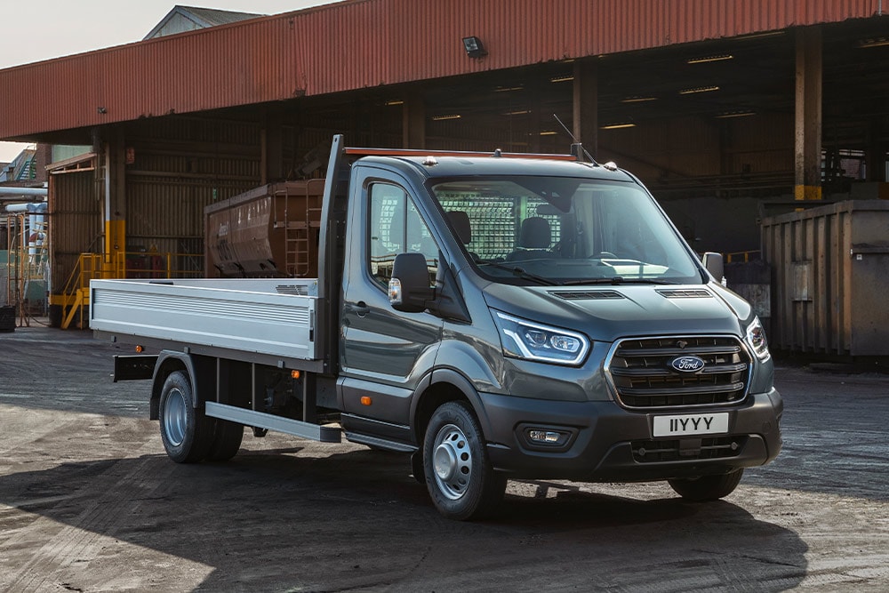 Een Ford Transit-chassis met cabine geparkeerd op een industrieterrein. 