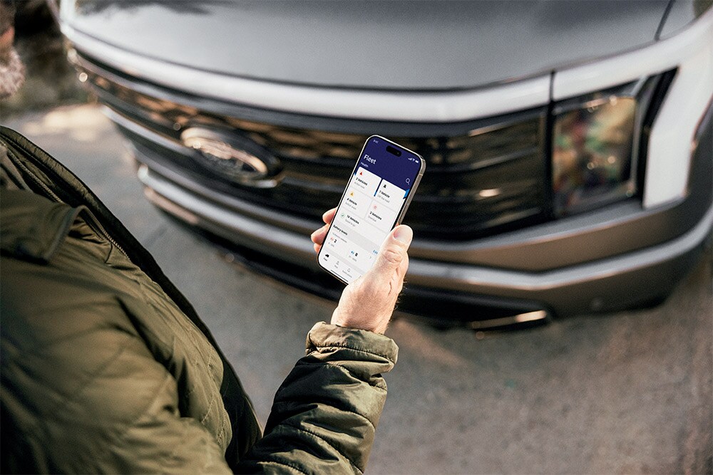 Een man kijkt op zijn smartphone voor een Ford Ranger.