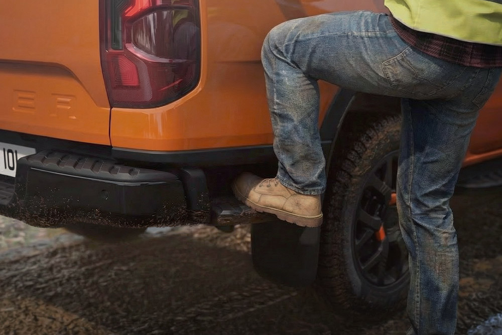 Een bouwvakker die op de geïntegreerde achterste trede van de Ford Ranger stapt.