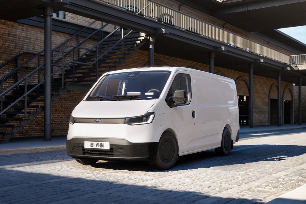 Een witte Ford Transit City® L1H1-bestelwagen staat geparkeerd voor een bakstenen gebouw.