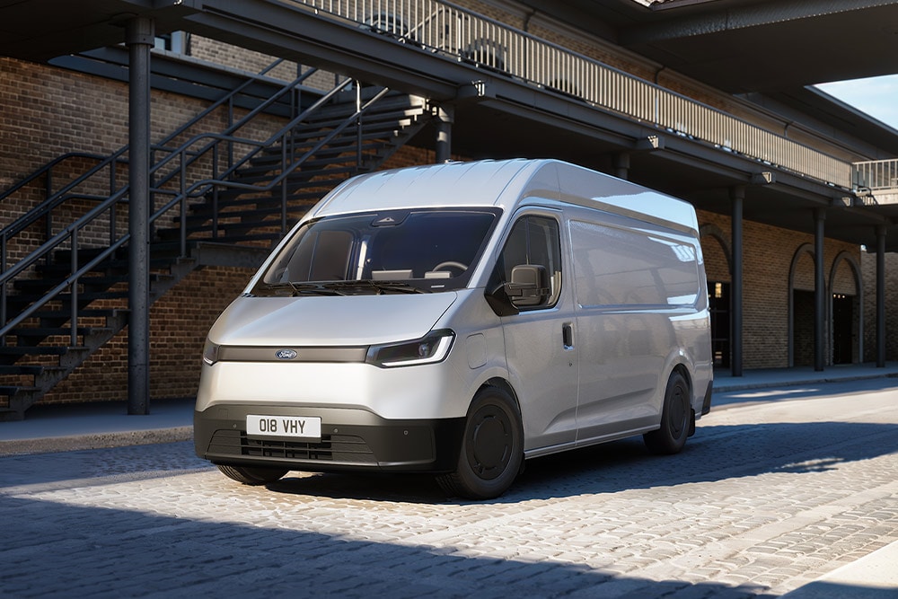 Een witte Ford Transit City® L2H2-bestelwagen staat geparkeerd voor een bakstenen gebouw.