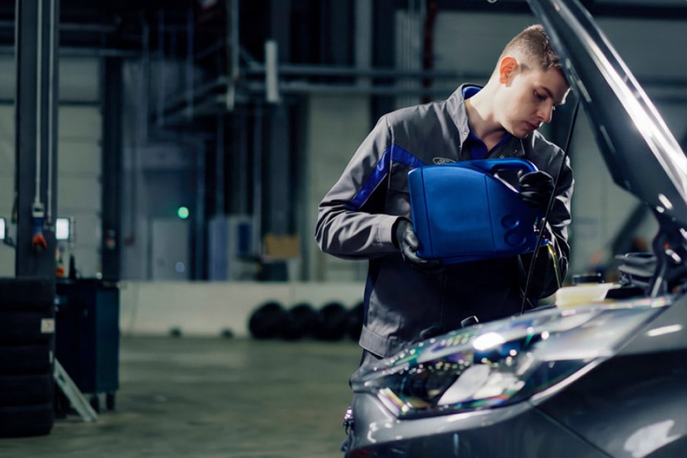 Zijaanzicht van een door Ford erkende technicus die reparaties uitvoert aan een voertuig in een garage.