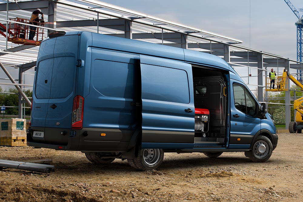 Blauwe Ford Pro Transit bestelwagen geparkeerd op een bouwplaats.