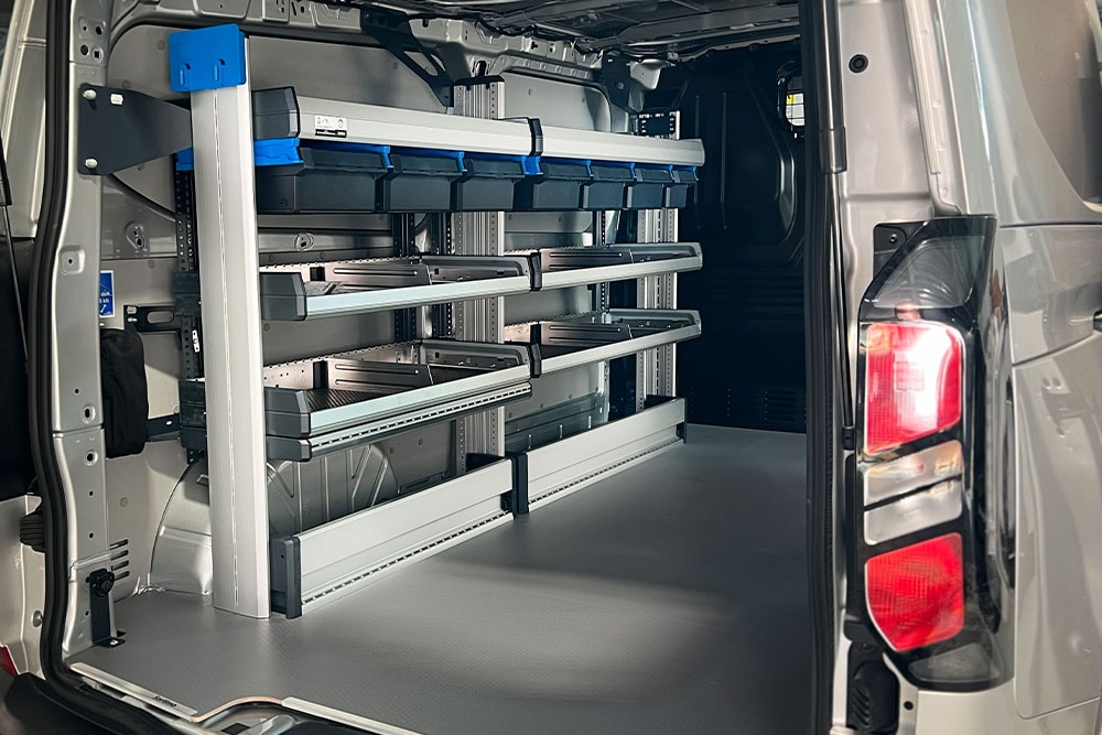 Achterinterieur van een Ford Transit bestelwagen, met een modulair rekkensysteem met diverse opbergbakken.