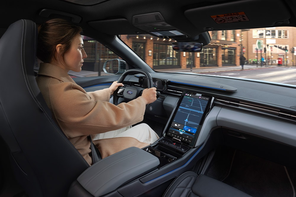 Iemand die in een Ford-voertuig rijdt, met een groot touchscreen in het midden waar de navigatie op staat.