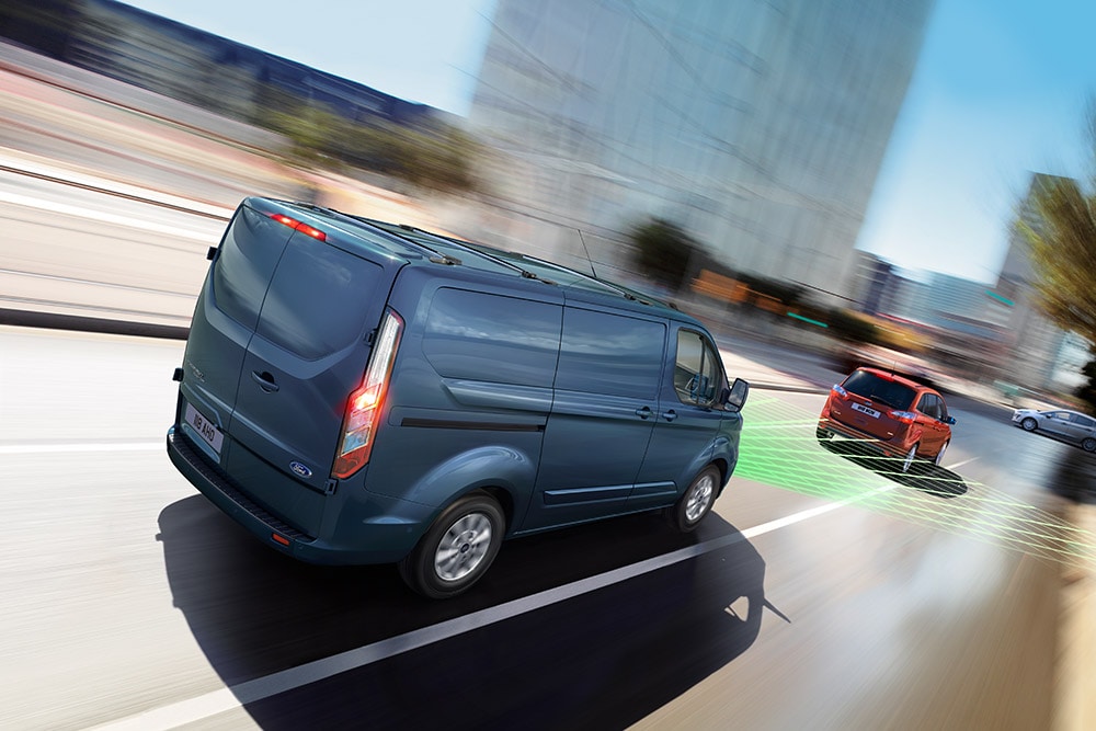 Achteraanzicht van een blauwe Ford-bestelwagen, met groene lijnen die de rijhulpfuncties aangeven.