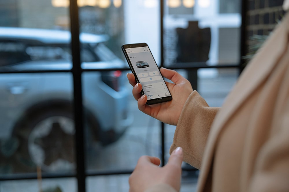 Een persoon met een smartphone waarop de FordPass-app te zien is met informatie over het wagenparkbeheer.