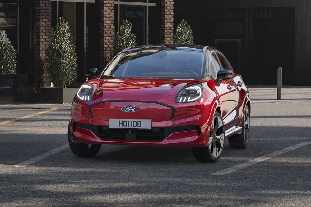 Een rode elektrische Ford Puma Gen-E die op een stadsweg rijdt.