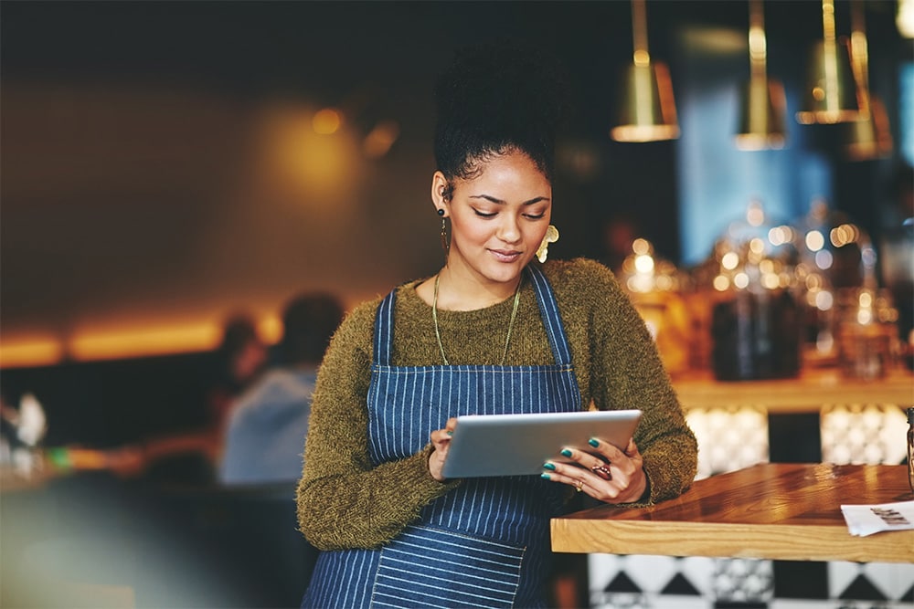 Een restauranteigenares die de belasting van haar auto van de zaak controleert op een tablet.