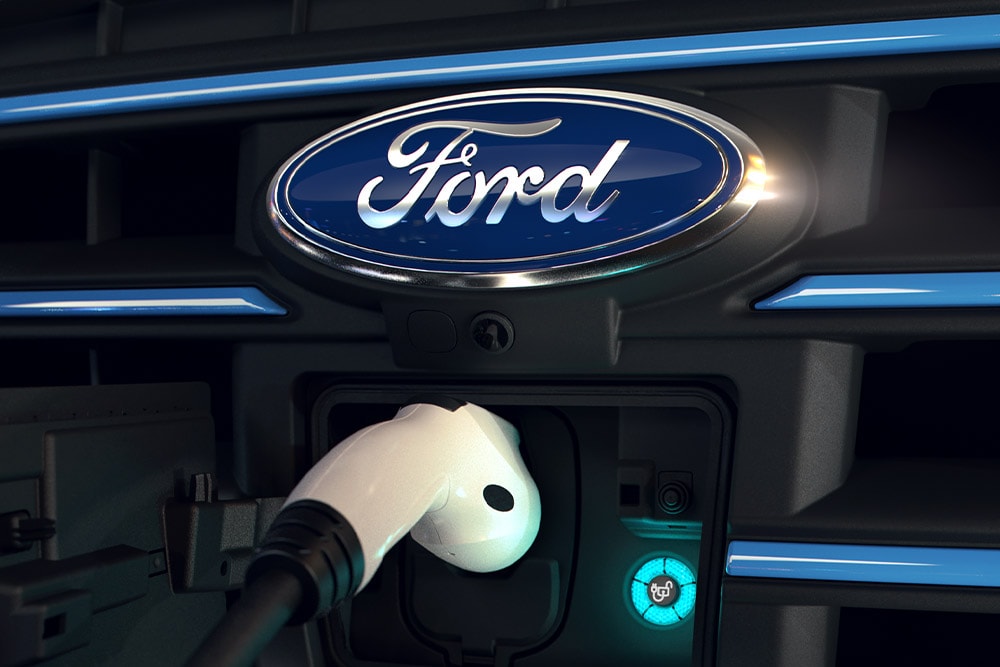 Close-up van een witte oplaadkabel die in de oplaadpoort aan de voorkant van een elektrisch voertuig van Ford zit.