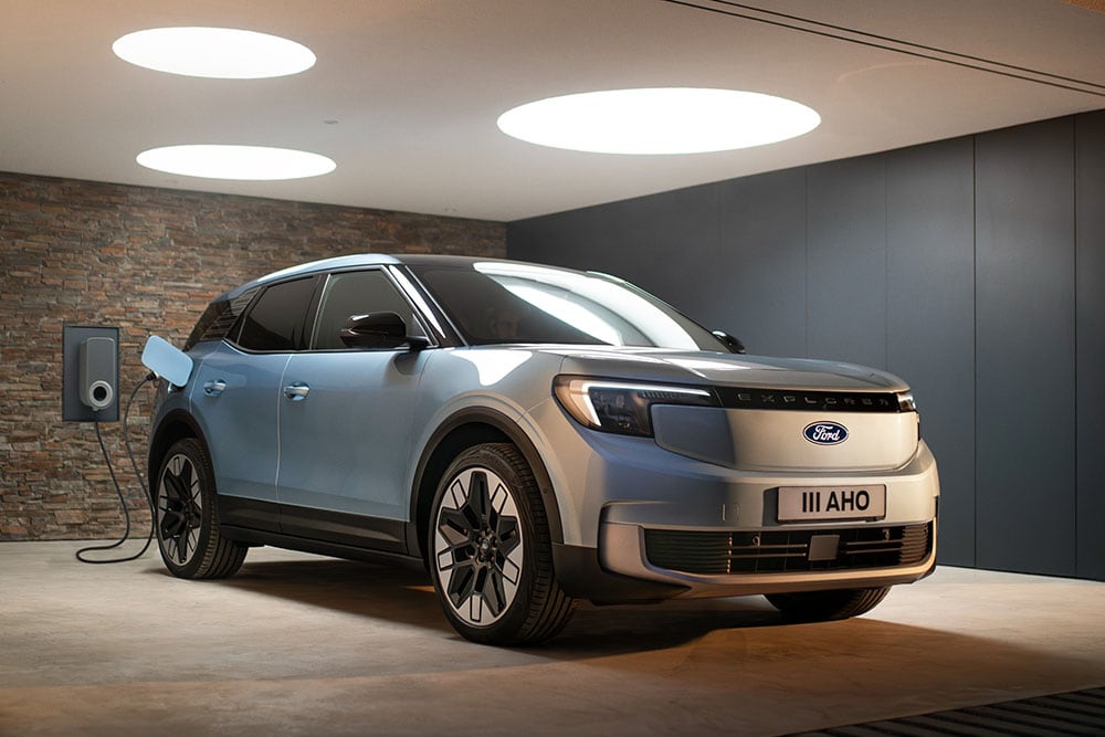 Vooraanzicht van een lichtblauwe Ford Explorer die wordt opgeladen in een moderne garage met ronde lampen.