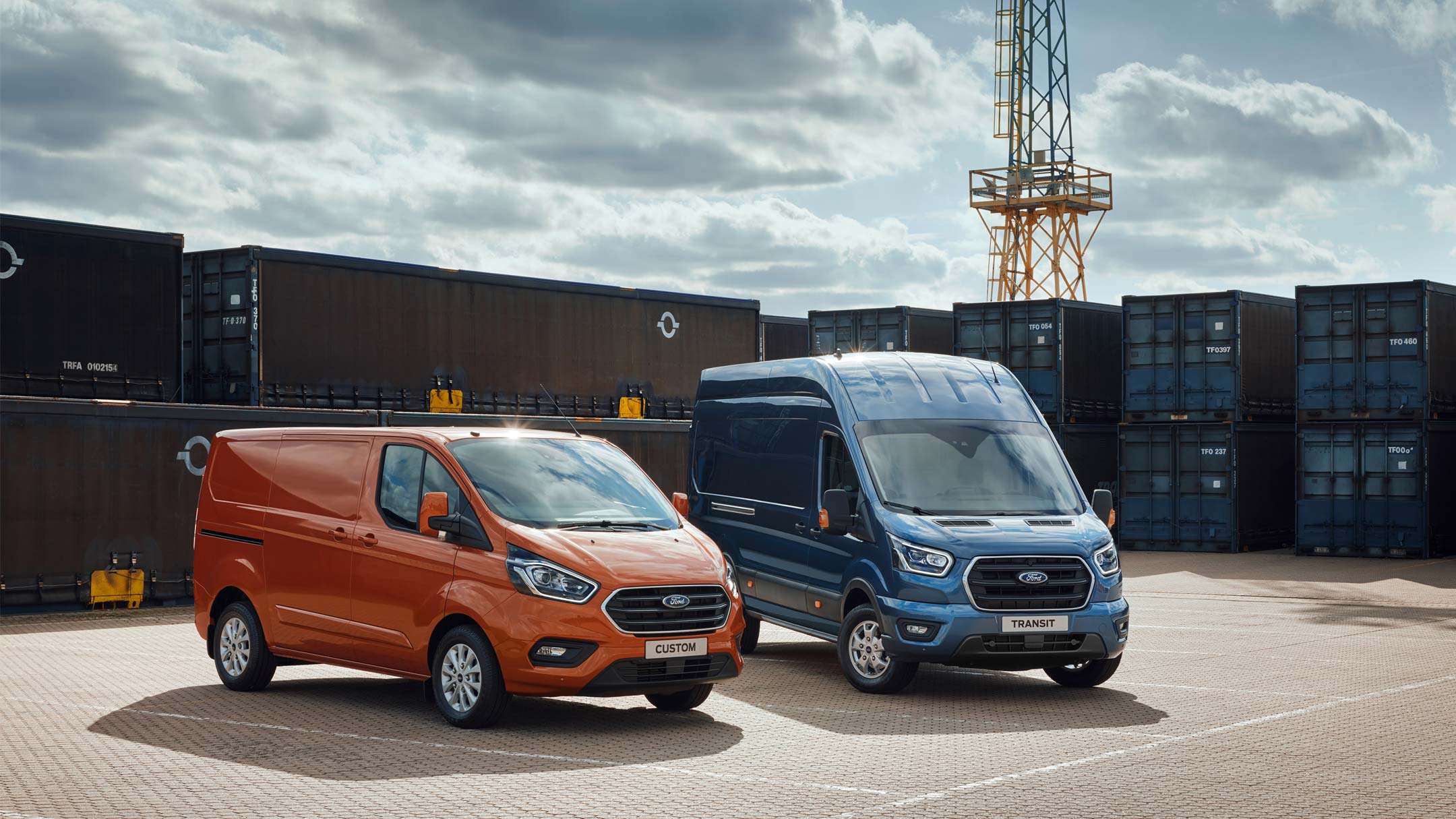 A Transit Custom and a Transit Van parked in front of containers